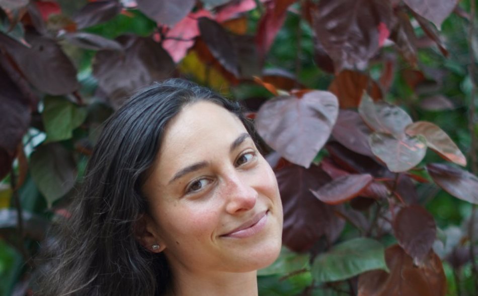 Madeline smiling in front of red and green foliage